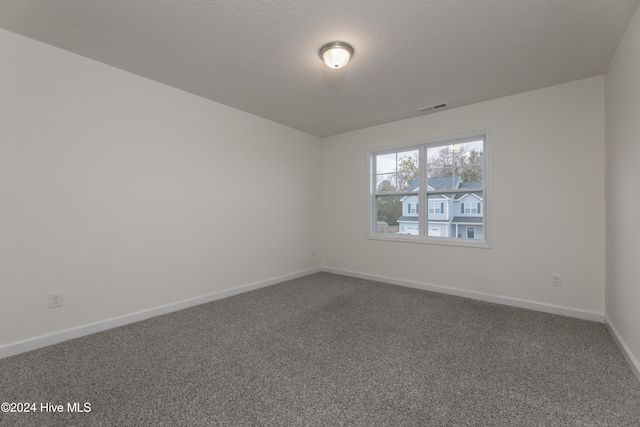 empty room with a textured ceiling and carpet flooring