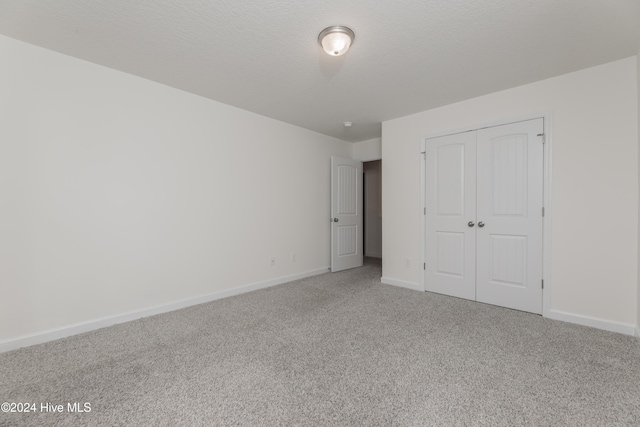 unfurnished bedroom with a textured ceiling, a closet, and carpet floors