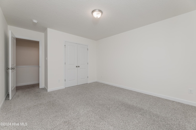 unfurnished bedroom with carpet floors, a textured ceiling, and a closet