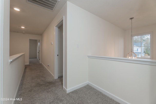 corridor featuring carpet floors and an inviting chandelier