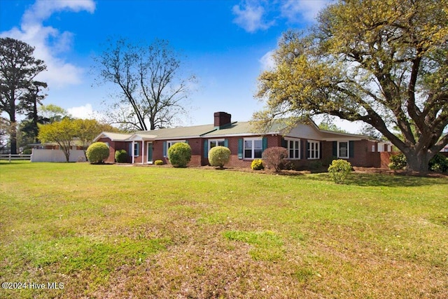 ranch-style home featuring a front lawn, a chimney, and brick siding