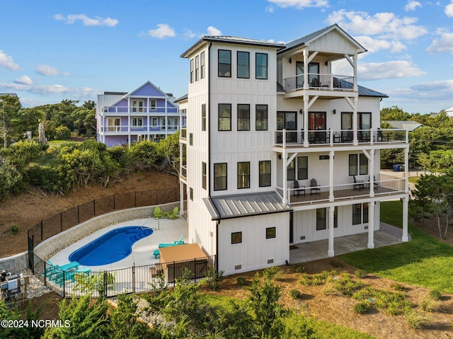 back of property featuring a balcony, a fenced in pool, and a patio area