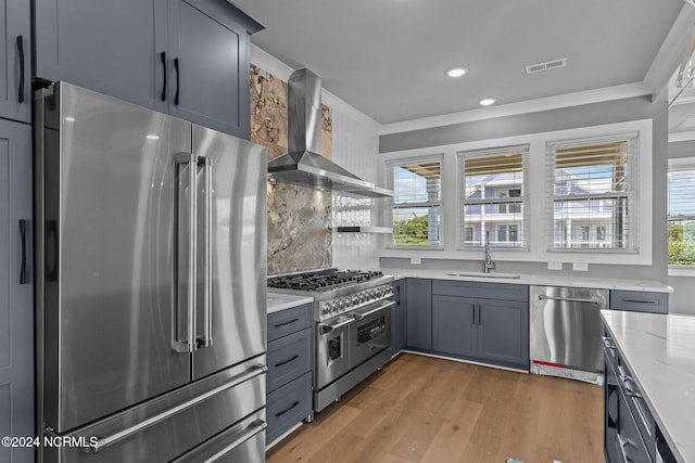 kitchen featuring gray cabinetry, sink, hardwood / wood-style flooring, high quality appliances, and wall chimney exhaust hood