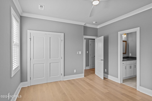 unfurnished bedroom featuring ceiling fan, crown molding, connected bathroom, a closet, and light wood-type flooring