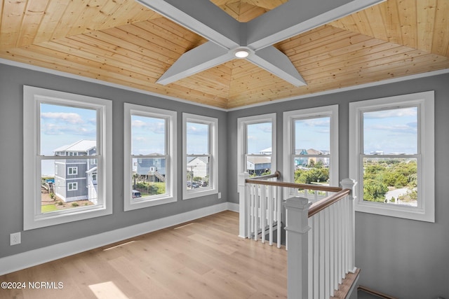 unfurnished sunroom with wood ceiling, a healthy amount of sunlight, and beam ceiling