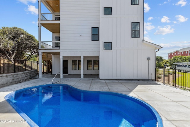 rear view of house with a balcony, a fenced in pool, and a patio