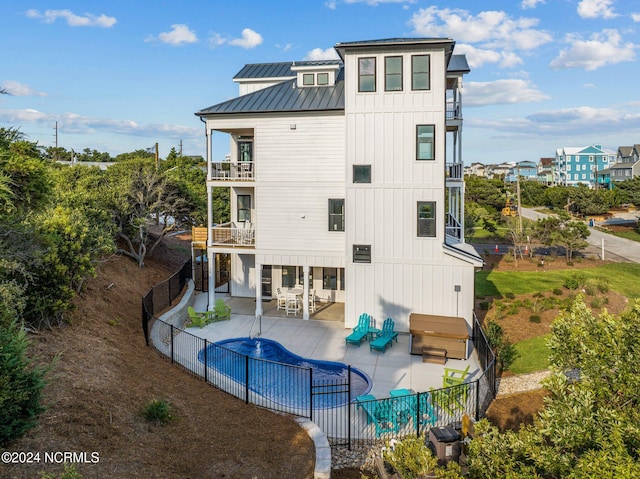 rear view of property with a balcony, a covered pool, and a patio