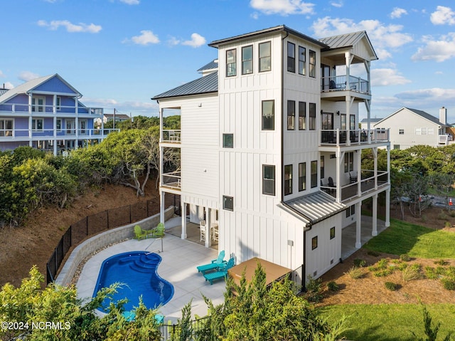 back of property with a fenced in pool, a patio, and a balcony