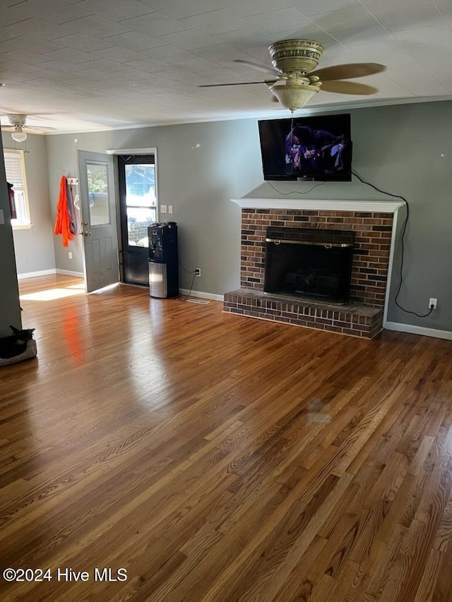 unfurnished living room with a brick fireplace, hardwood / wood-style flooring, and ceiling fan