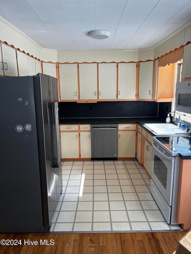 kitchen with light tile patterned floors, appliances with stainless steel finishes, backsplash, ornamental molding, and sink