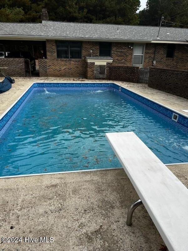 view of swimming pool with a diving board