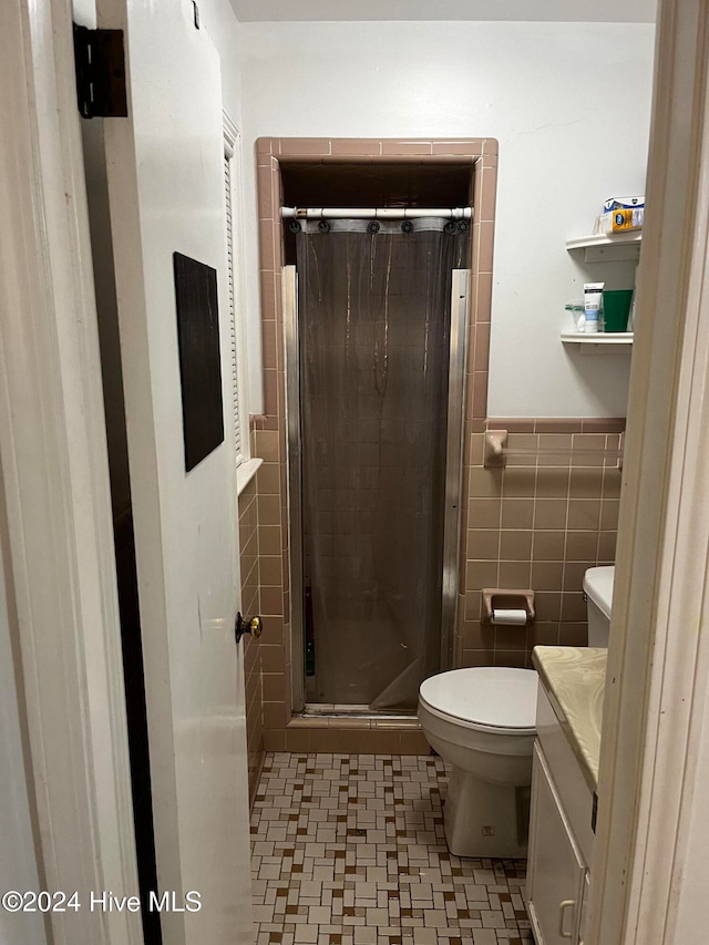 bathroom featuring vanity, toilet, walk in shower, and tile walls