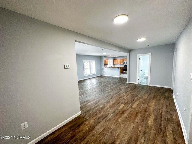 unfurnished living room with dark wood-type flooring