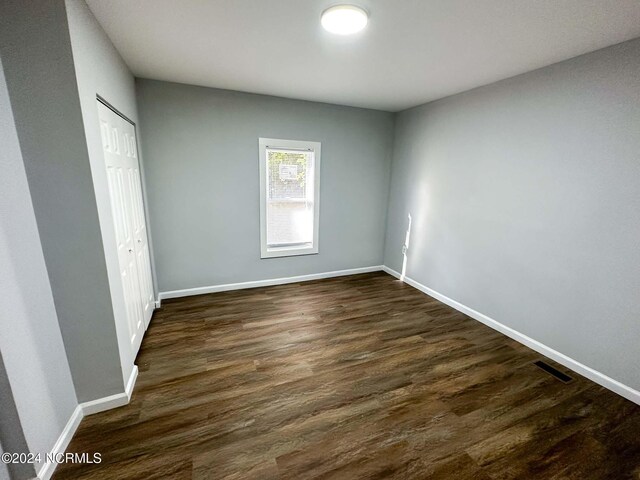 unfurnished bedroom featuring a closet and dark hardwood / wood-style flooring