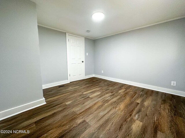 spare room featuring ornamental molding and dark hardwood / wood-style floors