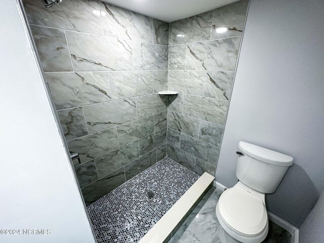 bathroom featuring a tile shower and toilet