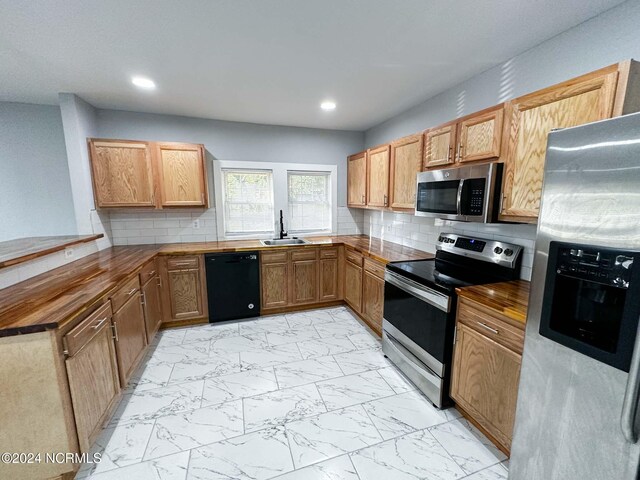 kitchen featuring tasteful backsplash, appliances with stainless steel finishes, sink, and kitchen peninsula