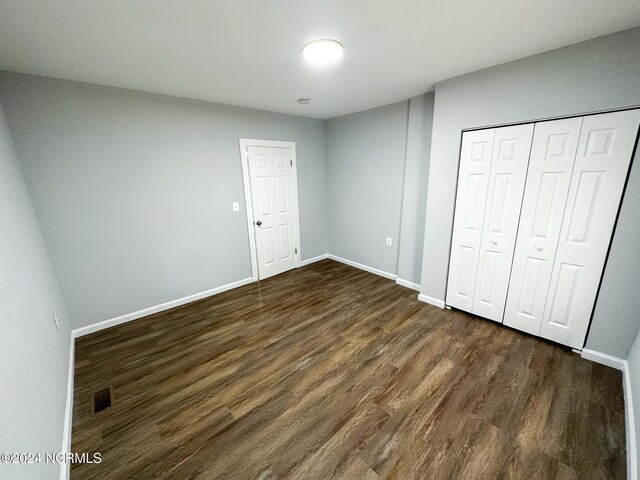 unfurnished bedroom featuring a closet and dark hardwood / wood-style floors