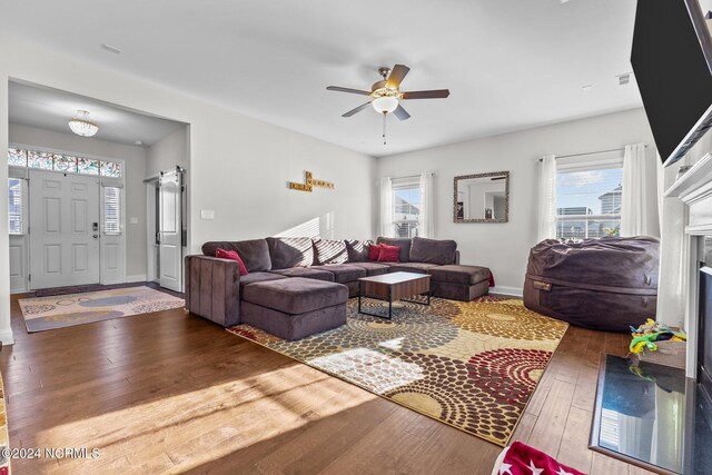 living room with a premium fireplace, dark hardwood / wood-style floors, ceiling fan, and a wealth of natural light