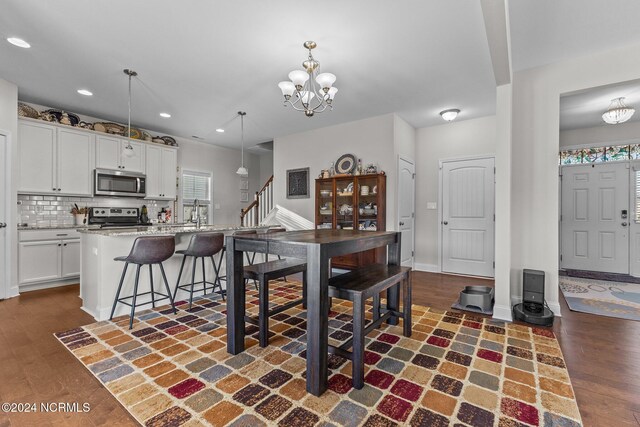 kitchen with appliances with stainless steel finishes, white cabinets, sink, and pendant lighting