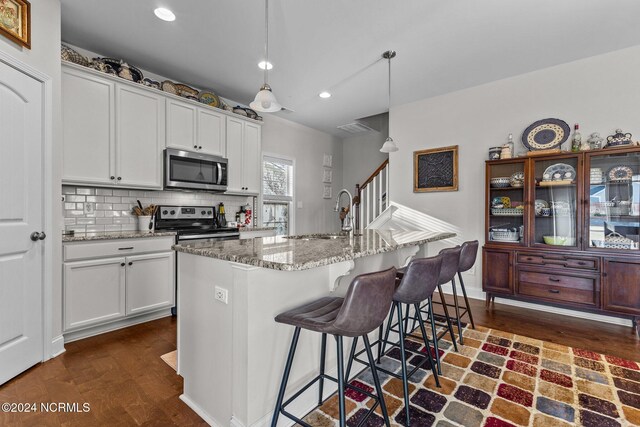 kitchen with appliances with stainless steel finishes, sink, pendant lighting, and white cabinets