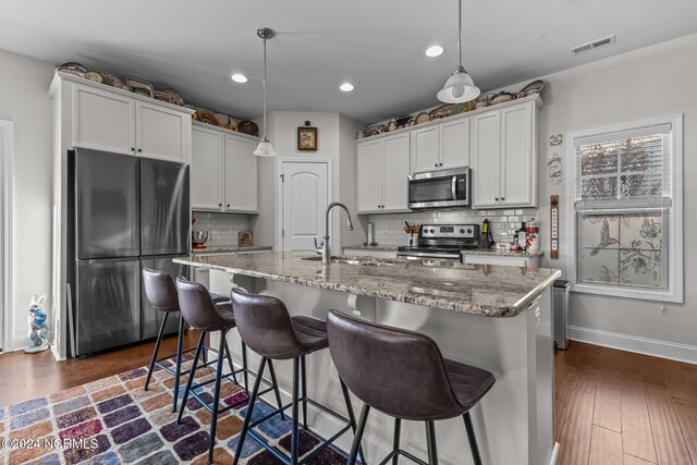 kitchen with sink, appliances with stainless steel finishes, decorative light fixtures, and white cabinetry