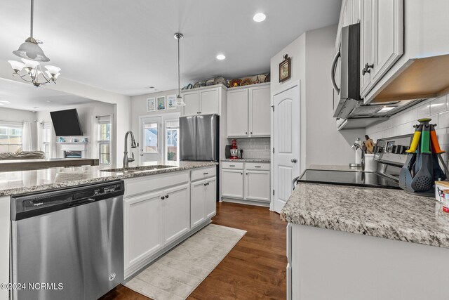 kitchen with white cabinets, dark hardwood / wood-style flooring, appliances with stainless steel finishes, decorative light fixtures, and sink