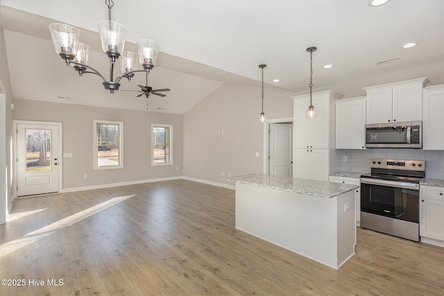 kitchen featuring white cabinetry, stainless steel appliances, decorative light fixtures, and a kitchen island