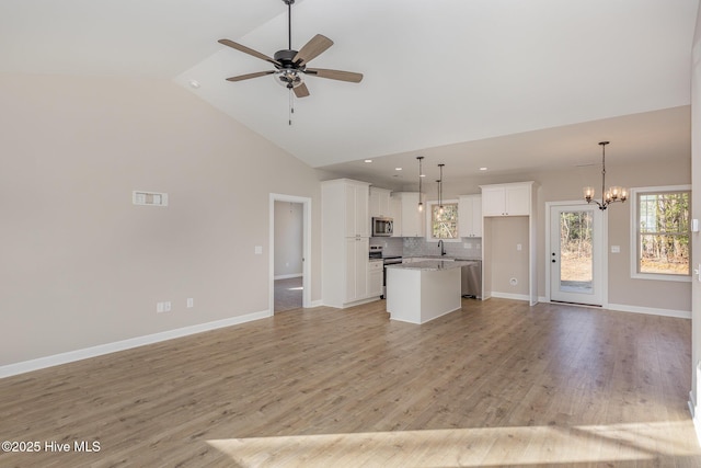 kitchen with white cabinetry, stone countertops, a kitchen island, pendant lighting, and stainless steel appliances