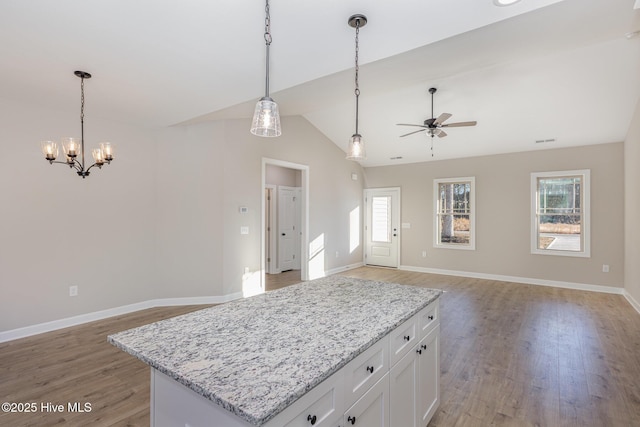 kitchen with a kitchen island, plenty of natural light, white cabinets, and decorative light fixtures