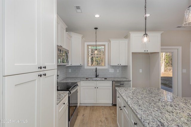 kitchen with sink, tasteful backsplash, decorative light fixtures, appliances with stainless steel finishes, and white cabinets