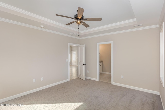 unfurnished bedroom featuring ornamental molding, a tray ceiling, connected bathroom, and light carpet