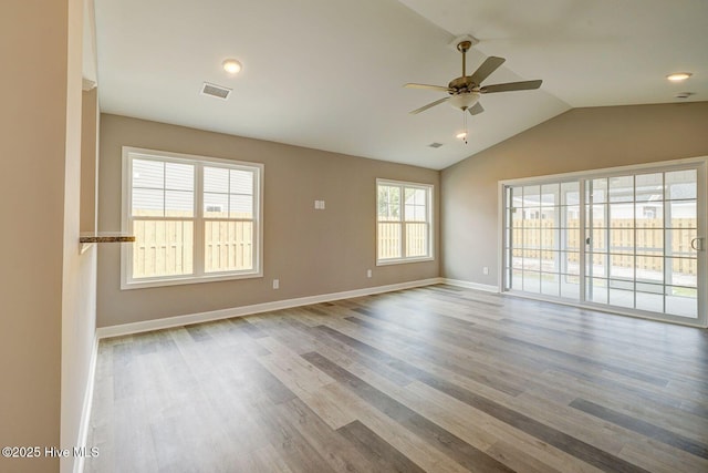 spare room featuring vaulted ceiling, baseboards, visible vents, wood finished floors, and ceiling fan