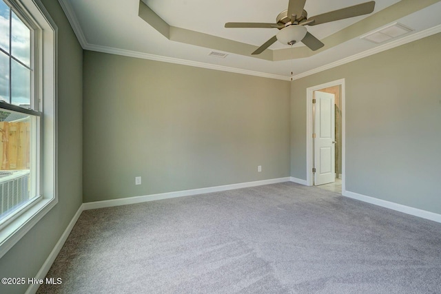 carpeted spare room featuring a tray ceiling, visible vents, a wealth of natural light, and ceiling fan