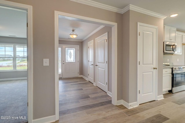 entryway with baseboards, light wood-style floors, and ornamental molding