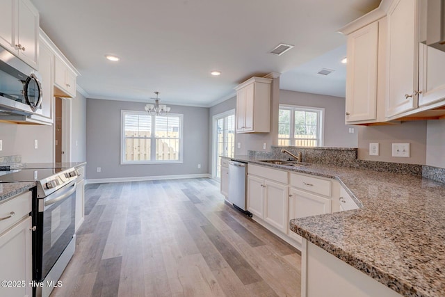 kitchen featuring visible vents, a sink, light wood-style flooring, appliances with stainless steel finishes, and a notable chandelier