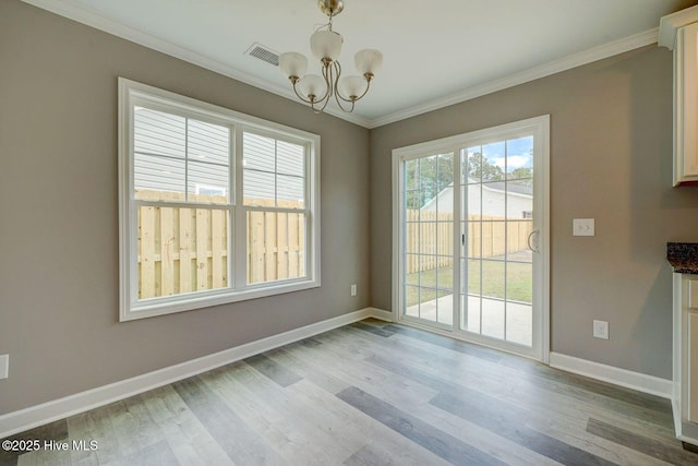 unfurnished dining area featuring crown molding, wood finished floors, an inviting chandelier, baseboards, and visible vents