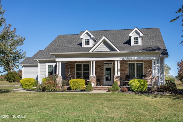 view of front facade with stone siding, a porch, roof with shingles, and a front yard