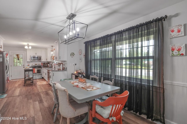 dining space featuring a wealth of natural light, sink, light hardwood / wood-style floors, and a notable chandelier