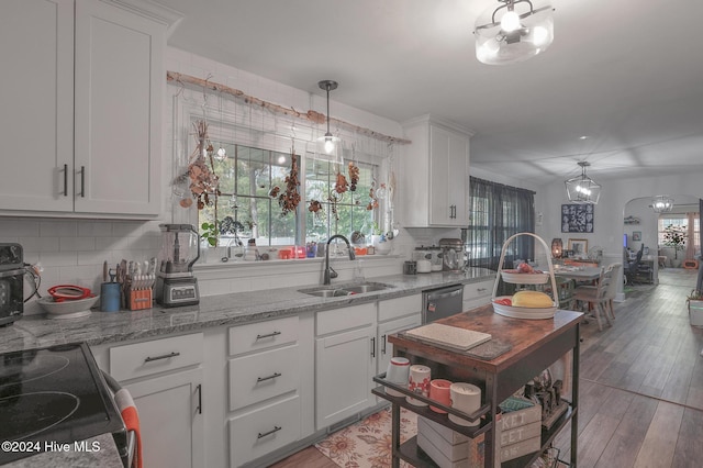 kitchen featuring light hardwood / wood-style floors, white cabinetry, sink, backsplash, and hanging light fixtures