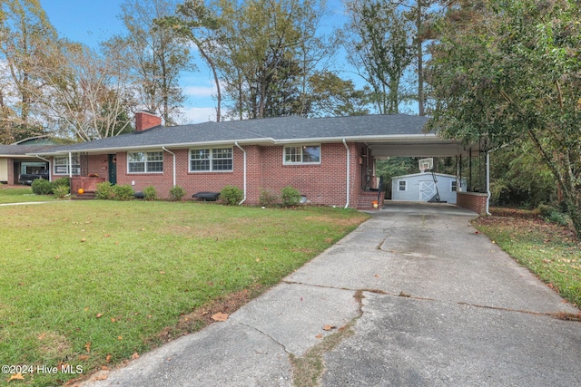 ranch-style home with a carport, a front lawn, and a storage unit