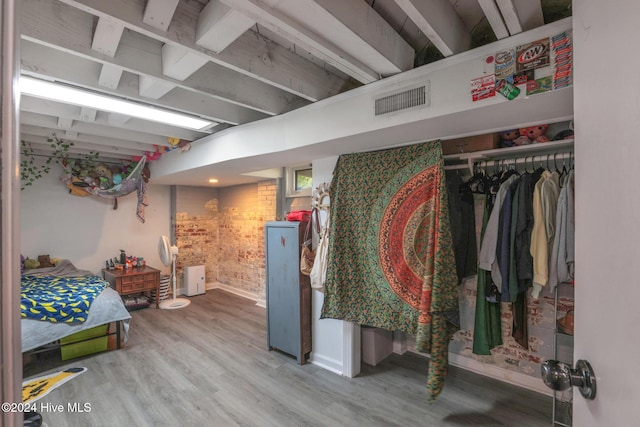 bedroom featuring brick wall and wood-type flooring