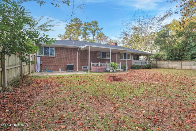 back of property with central air condition unit, a hot tub, and a patio area