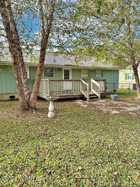 rear view of house with a wooden deck and a lawn