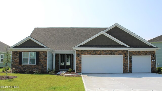 craftsman-style house featuring a front lawn and a garage