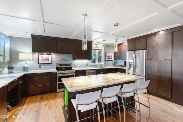 kitchen with tasteful backsplash, a breakfast bar area, light hardwood / wood-style flooring, sink, and stainless steel appliances