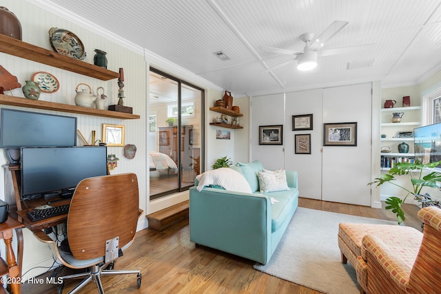 living room with ceiling fan, ornamental molding, light hardwood / wood-style flooring, and built in shelves