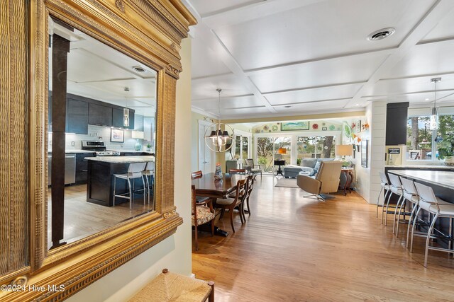 living room with a wealth of natural light, lofted ceiling, a chandelier, and light wood-type flooring