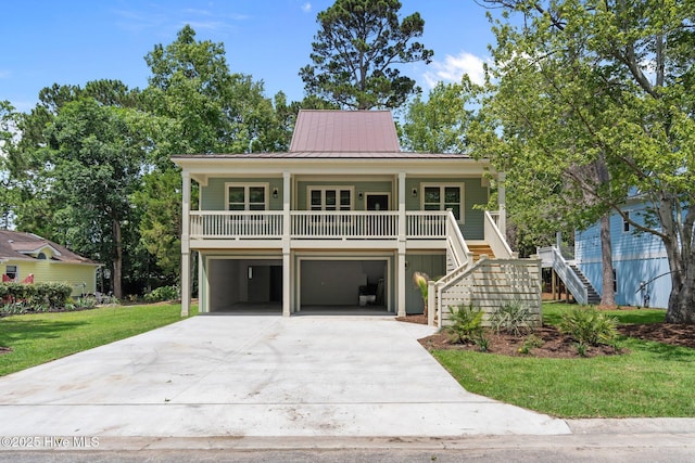 1552 Windsong Dr SW, Ocean Isle Beach, NC 28469 - beach home with covered porch, stairway, concrete driveway, a standing seam roof, and a front lawn