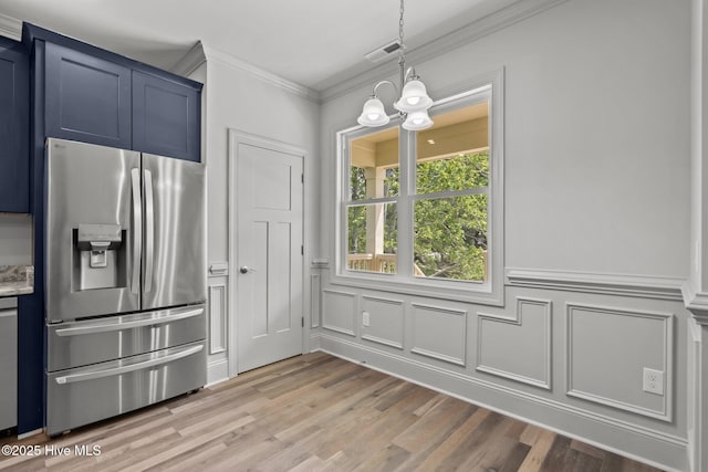 1552 Windsong Dr SW, Ocean Isle Beach, NC 28469 - kitchen featuring stainless steel refrigerator with ice dispenser, ornamental molding, blue cabinets, a decorative wall, and hanging light fixtures